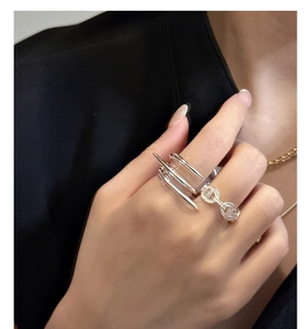 Detail of 925 sterling silver crossover nail and chain style rings on a female hand