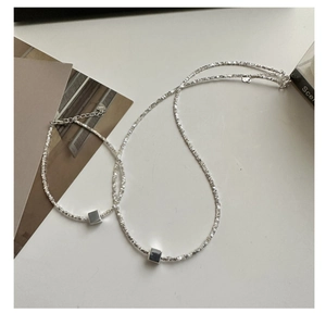 Détail macro du collier en argent S925 montrant le pendentif cube et la chaîne texturée