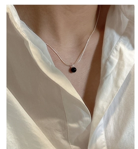 Detailed view of silver snake chain necklace featuring a minimalist black onyx bead pendant