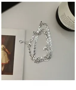 Dettaglio della collana a catena naso di maiale in argento S925 con logo su tavolo