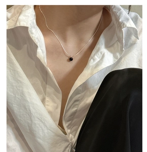 Close-up of minimalist S925 silver snake chain necklace with a glossy black onyx bead pendant
