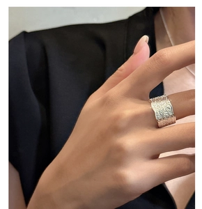 Detail of S925 sterling silver wide band ring with embossed scroll pattern and wavy edges