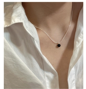 Close-up of S925 silver necklace with black agate bead pendant on a model neck