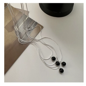 Detailed view of silver S925 snake chains with black onyx sphere pendants on display