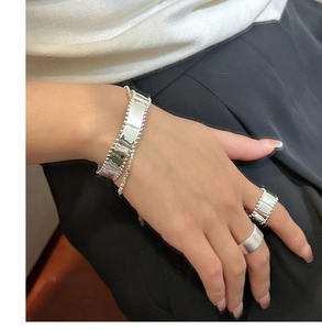 Detail view of wide wave-edge silver bead cuff bracelet and matching minimalist rings