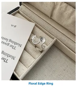 Macro shot of silver S925 ring with wavy floral texture in a beige jewelry box