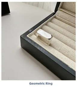 Détail d'une bague géométrique carrée en argent poli dans son écrin à bijoux noir