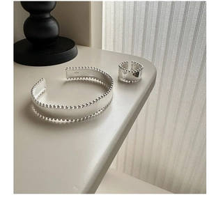 Macro detail of S925 sterling silver cuff bracelet and ring set with beaded edges