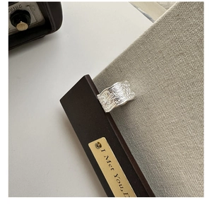 Macro detail of wide S925 silver ring featuring intricate vintage floral vine engraving