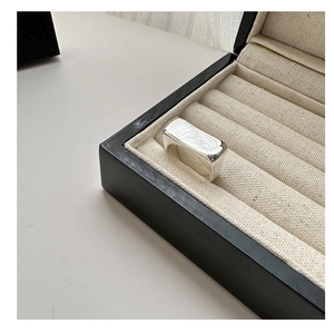 Détail d'une bague carrée en argent avec texture ondulée sur support en lin