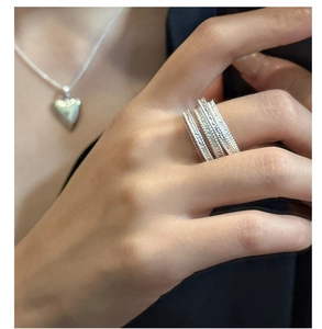 Detail of layered S925 sterling silver rings with textured finish on model's hand