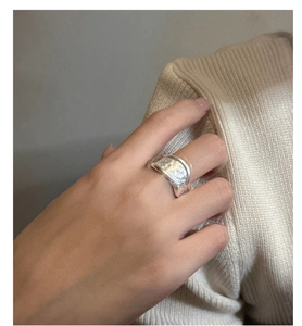 Detail of wide matte sterling silver ring with organic hand-hammered texture on model