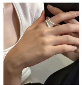 Detail of wide matte S925 sterling silver ring with handmade hammered texture on finger
