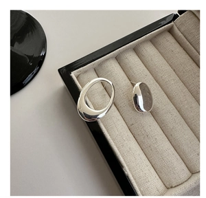 Detailed view of asymmetric S925 silver hollow and solid oval earrings in a jewelry box