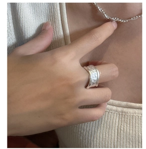 Detail of silver textured wide ring with rock pattern finish worn on model