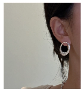 Close-up of asymmetrical S925 sterling silver oval hoop earrings worn by a model