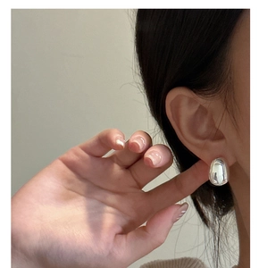 Close-up of polished S925 sterling silver teardrop stud earrings worn by a model