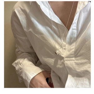 Détail d'un long collier à boule en argent sterling 925 sur une chemise blanche