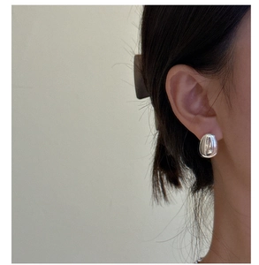 Close-up of a silver teardrop earring on model with polished mirror finish and minimal style