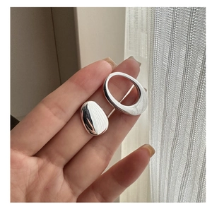Macro shot of asymmetric S925 silver earrings with polished oval and pebble design
