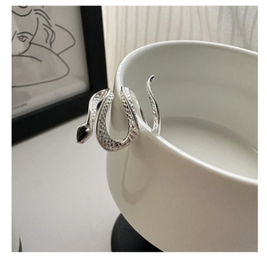 Macro shot of S925 sterling silver snake ring with black zircon stone on white ceramic cup