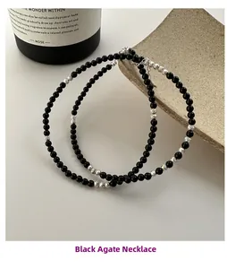 Close-up of black onyx beaded necklace with silver metallic accents and lobster clasp detail