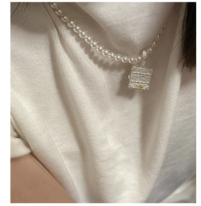 Close-up of S925 silver chest pendant with intricate engraving on a pearl necklace