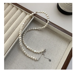 Detail of S925 sterling silver heart tag and irregular baroque pearls on jewelry tray