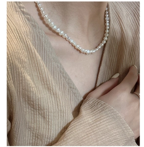 Detailed view of elegant white pearl necklace worn on neck with striped fabric