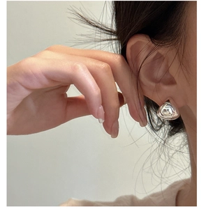 Close-up of a minimalist silver irregular triangular stud earring worn on ear
