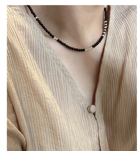Close-up of black agate beaded necklace with silver accents on a minimalist model neckline