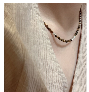 Détail d'un collier de perles en œil de tigre avec accents floraux sur un mannequin