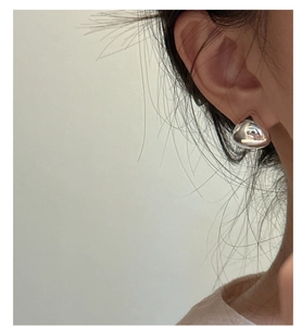 Close-up of minimalist silver water drop earrings with a polished metallic finish