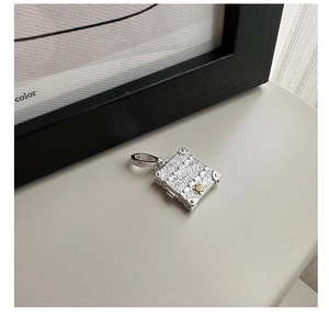 Macro shot of S925 sterling silver suitcase pendant with gold floral relief and scroll pattern