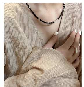 Detail of minimalist S925 silver necklace with black agate beads on a linen fabric background