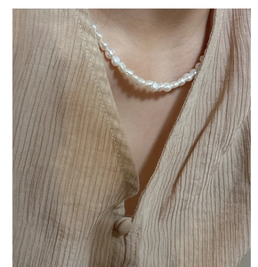 Detail of baroque freshwater pearl necklace worn by model with natural white luster