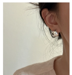 Close-up of polished S925 sterling silver drop earrings worn on ear with mirror finish