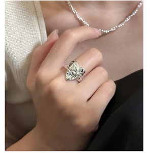 Detailed view of silver heart ring with hammered lava texture on model's hand