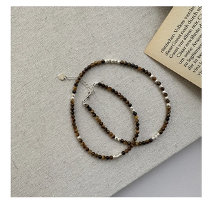 Détail du collier de perles en œil de tigre avec fermoir cœur en argent S925 sur lin