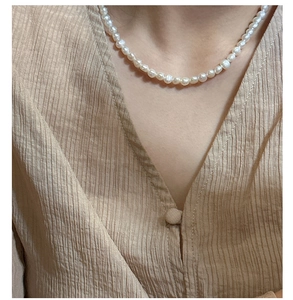 Close-up of elegant S925 silver pearl necklace worn by a model in a V-neck blouse