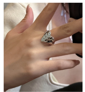 Detail shot of a silver heart-shaped ring with hammered texture worn on the finger