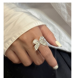 Detailed shot of textured silver bow ring with intricate 3D pleated wing patterns