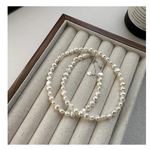 Detail of baroque pearl necklace with S925 silver clasp on velvet jewelry tray