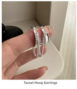 Detailed view of silver S925 sterling silver tassel drop earrings held in hand