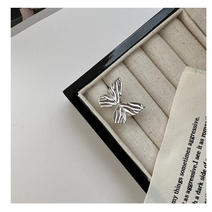 Detailed top view of a textured silver bow ring resting on a beige velvet jewelry case