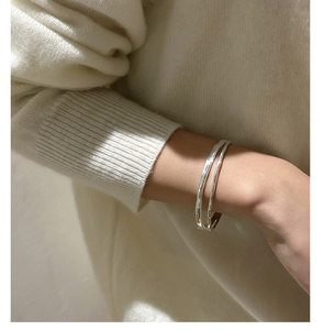 Detail of 925 sterling silver double-layered hammered bracelet on a knitted sleeve