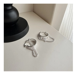 Detail of silver S925 minimalist hoop earrings with hanging Cuban link chain design