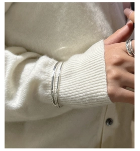 Detail of a minimalist silver layered texture bracelet and ring set on model