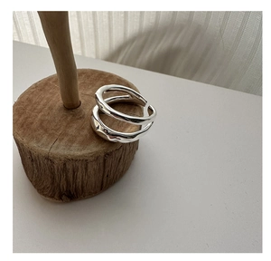 Détail d'une bague double couche en argent S925 avec texture lave sur socle en bois