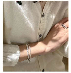Detail of minimalist silver double-layer textured bracelet and ring on a female model